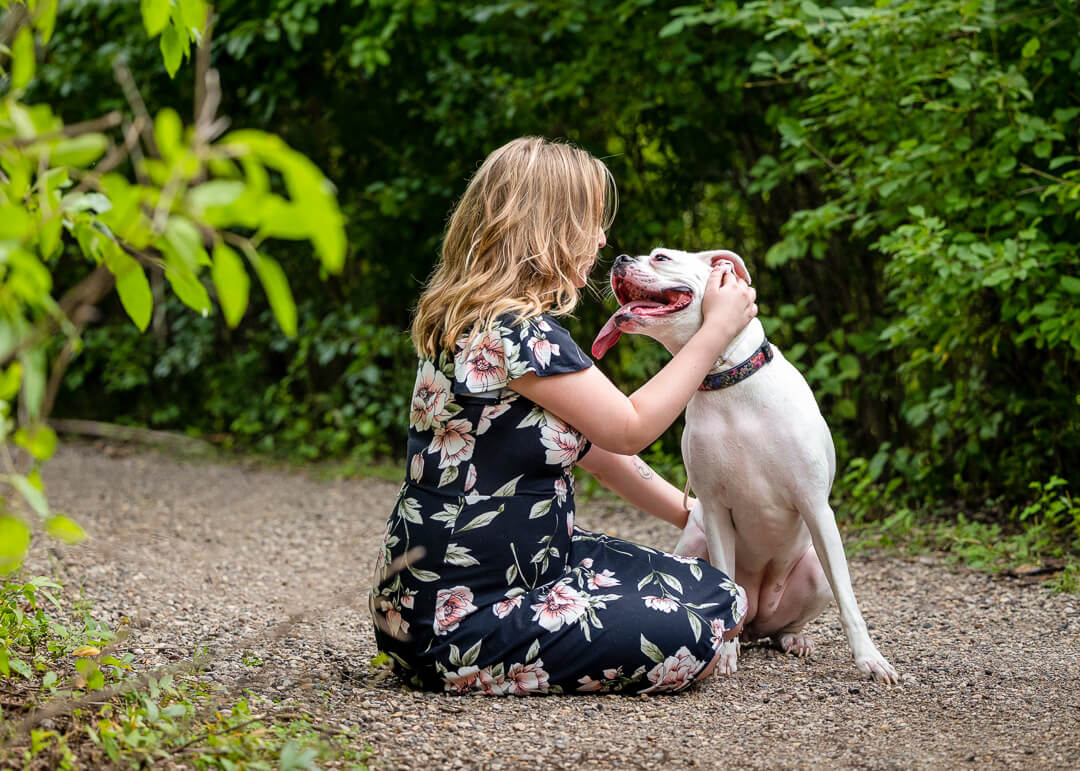White boxer sitting with her owner and looking lovingly at her.